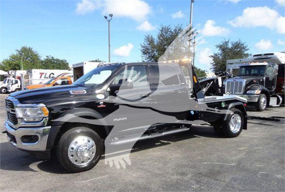 2023 Ram 5500 SLT single-cab tow truck in dealership lot with flatbed. Visible text includes RAM badge and SLT trim on side.