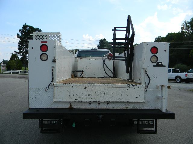 Ford F-750 service/utility truck bed showing rear with white flatbed, ladder rack, and tail lights.
