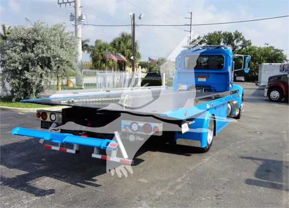 Peterbilt 337 tow truck flatbed rear view showing blue cab and flatbed titan style hoist with rear lights.