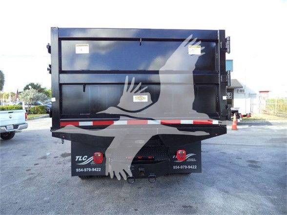 Rear view of a Freightliner truck dump bed with two taillights and a hitch; company decals visible with phone numbers.