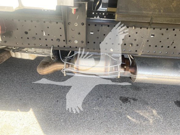 Isuzu NPR HD chassis exhaust pipe and undercarriage view with perforated frame and muffler visible.