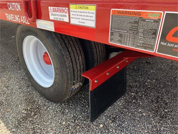 Container delivery trailer with single axle showing caution labels and a red mud flap attached near the wheel.