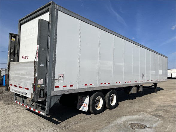 Semi trailer side view of a silver Vanguard dry van with rear doors, dual rear axles, and reflective red/white tape along the bottom edge.