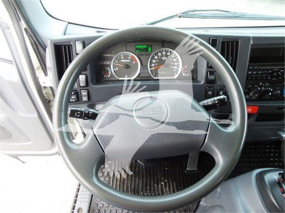 Isuzu NQR truck cabin interior showing steering wheel with gauge cluster and dashboard dials. Instrument panel includes round gauges and small digital display at top center.