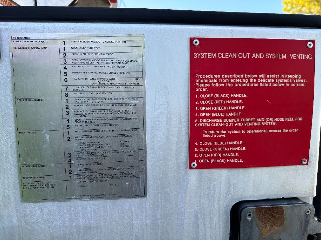Panel labels inside a 2001 Ford F550 fire truck showing instructions for system cleanout and venting with numbered steps and red instruction plate.