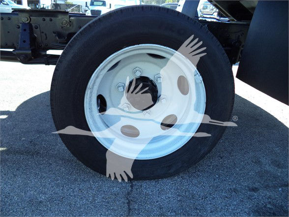 Isuzu NRR wheel and fender area showing wheel with white rim and black tire; background chassis frame.