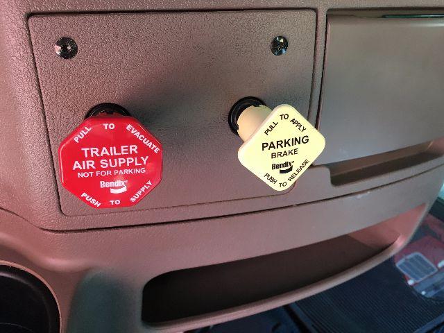 Conventional sleeper truck cab area showing two filler caps labeled PRIMING BRAKE FLUID 10 PL Quick view and TRL A AIR SUPPLY FILL.