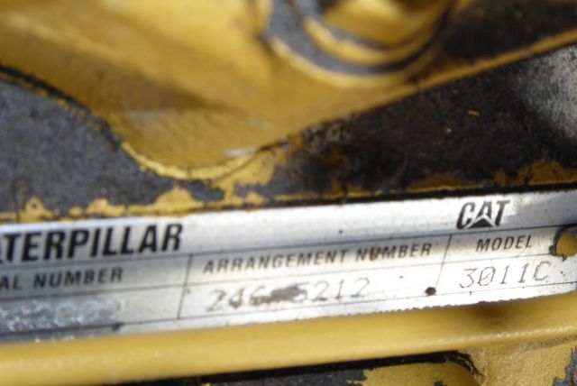 Caterpillar equipment identification plate with arrangement number 245-5212 and model number 3011C visible on a yellow machine.
