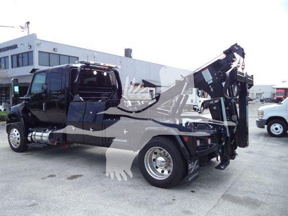 Tow truck with crane arm, side view showing branding and equipment. Visible text includes 'MV' on door and chrome fuel tank area, and a crane apparatus at rear.