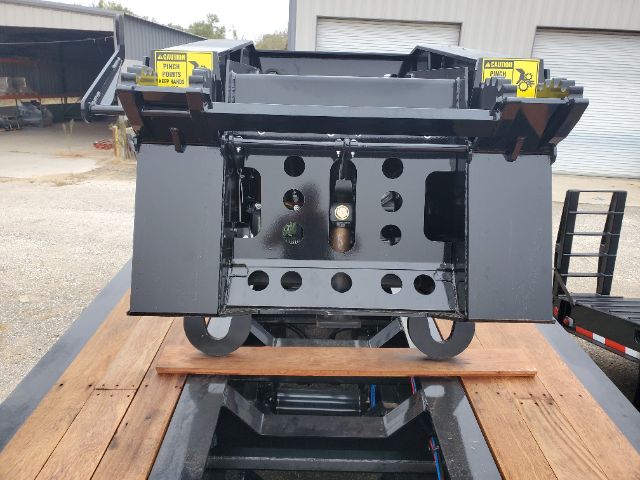 Back end of a lowboy trailer hitch mechanism with circular cutouts and a central vertical component. Visible are two yellow CAUTION panels on top corners and various holes and openings in a metal frame.
