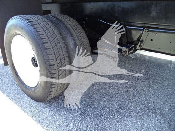 Ford E-450 chassis showing dual rear wheels and flatbed frame with suspension components.