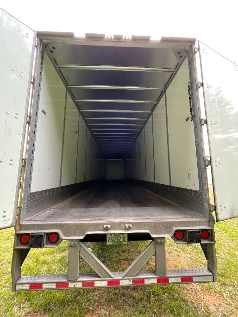 Trailer interior showing empty silver 53 ft van trailer with ribbed walls, rear doors open, and brand markings visible; inner floor and walls clean.