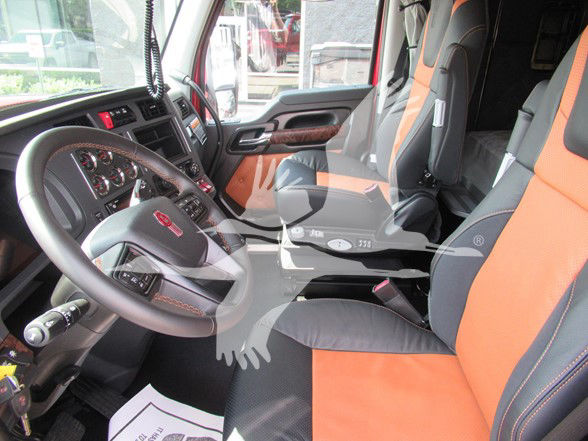 Kenworth W990 truck interior showing black and orange seats and dashboard with steering wheel.