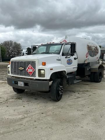 White Chevrolet Kodiak truck with a tank trailer, front view, stock number Unit 1. Diamond hazardous placard 1075 on the front, white cab, black bumper, side mirrors.