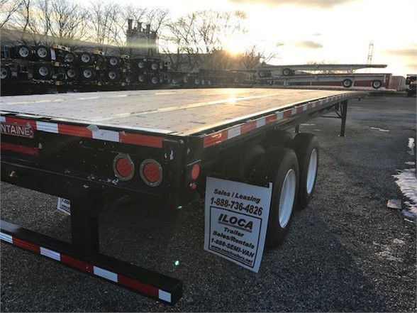 Flatbed trailer rear with dual axles and rear lights, Fontaine VELOCITY trailer in sunlight.