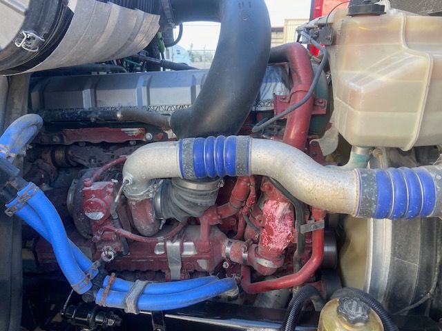 Mack CXU613 engine bay showing turbocharger, blue hoses, radiator overflow, and coolant reservoir.