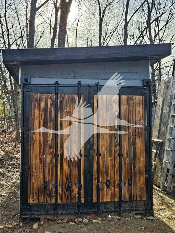 Container trailer with wooden doors and black metal frame. Front view showing split double doors with visible hinges and latches.
