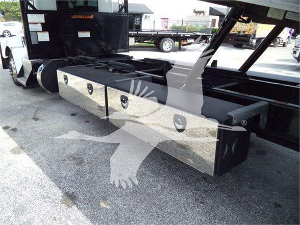 Kenworth T370 truck side view showing large aluminum storage boxes mounted under the frame and hydraulic or towing components.