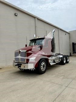 Kenworth T880 tractor cab front-left view showing large chrome grille and red exterior with white accent lines.