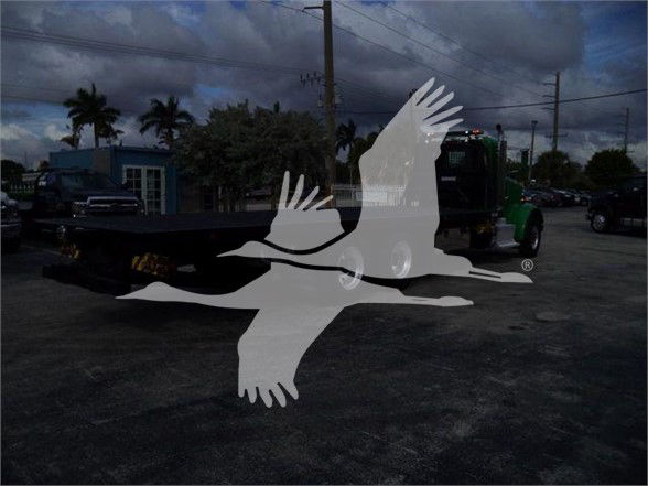 Truck flatbed with crane attachment in view; watermark of flying birds overlaying image. No legible vehicle branding or text visible in the foreground.