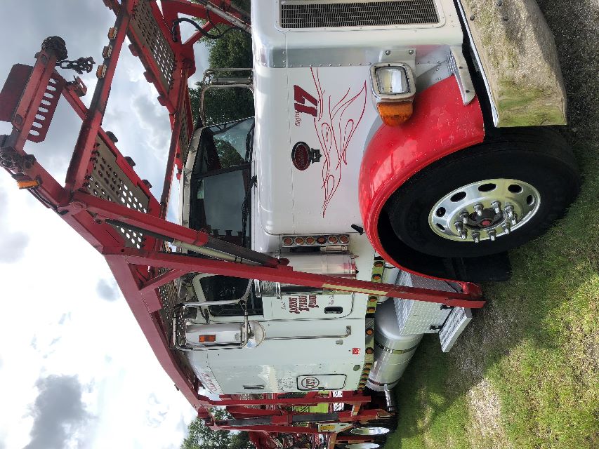 Peterbilt 379 heavy haul truck with red carrier frame on white cab, side text and number 17, front headlight, chrome bumper, large wheel, metal steps.