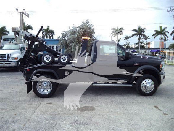 Ram 4500 Tow truck on lot with wheel lift equipment and black body, side view showing decals and chrome wheels.