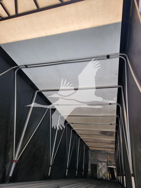 Trailer interior showing curtain side rails and overhead area with light panels; no legible model text visible.