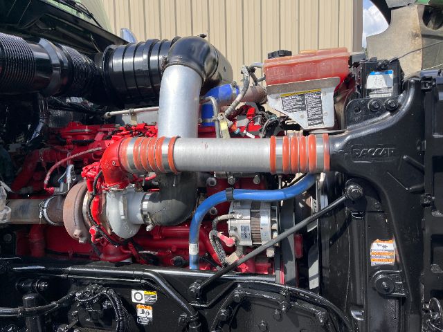 Kenworth T800 engine bay showing red engine, silver exhaust with orange-ribbed hose, blue coolant lines, and black radiator support.
