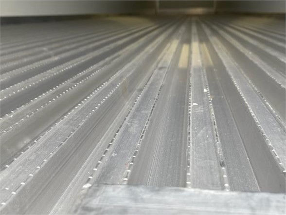 Trailer interior floor with ribbed metal surface and sparse debris, van-style reefer trailer.