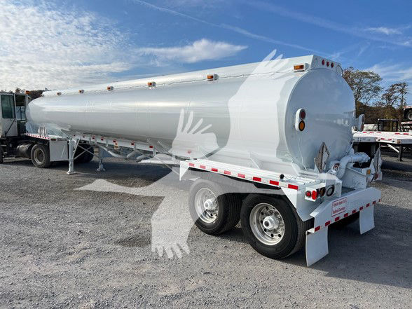 A Heil 9200 gallon trough bottom Petro Tank trailer in white, parked in a lot, viewed from the rear-right side showing triple-axle wheels and rear discharge assembly.