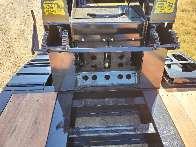 Front view of a 2021 Atoka RGN-553-E lowboy trailer transmission-like center area with hydraulic components, steel frames, and tie-down racks.