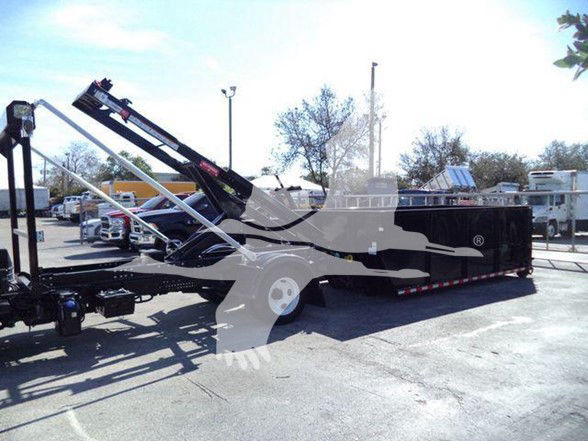 Isuzu NRR 2020 flatbed/utility truck with hydraulic loading ramp. Side view shows black equipment trailer body with white wheel, hoist/boom mechanism folded over top. No legible labels visible.