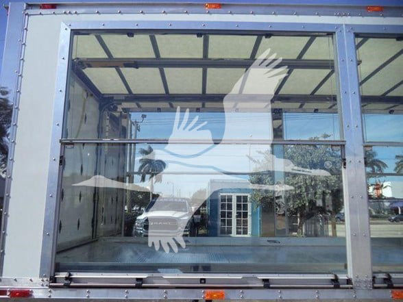 Kenworth T280 truck side/ rear view container with large glass rear door showing reflection of exterior and palm trees.