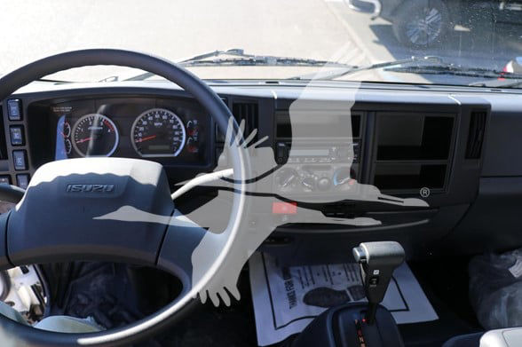 Isuzu FTR truck interior showing steering wheel, dashboard gauges, and gear shifter.