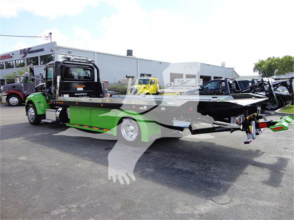 Tow truck with green and black color scheme, 2022 Peterbilt 337, flatbed wrecker body visible.