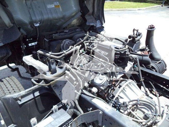 Isuzu NQR engine bay showing exposed diesel engine components and assorted hoses.