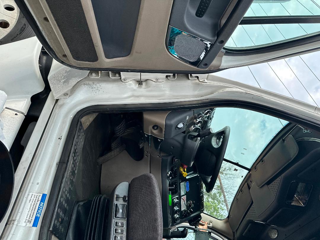 Cab interior of a 2011 Freightliner Cascadia truck showing steering wheel, dashboard, pedals, and open door frame.