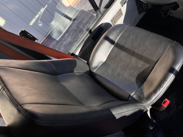 Operator seat in a 2013 Tico PROSPOTTER DOT truck with black leather/vinyl seat and red seatbelt buckle visible.