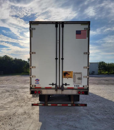 Rear view of a Utility 4000 D-X composite trailer showing rear doors, taillights, and an American flag sticker.