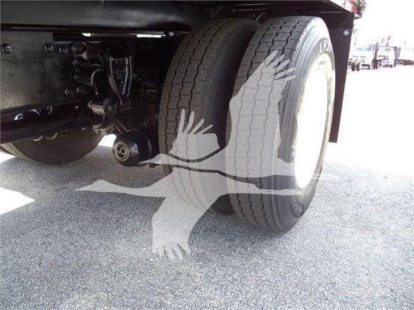 Truck rear dual wheels and undercarriage with some components visible; watermark graphic of a bird with wings spread across the image.