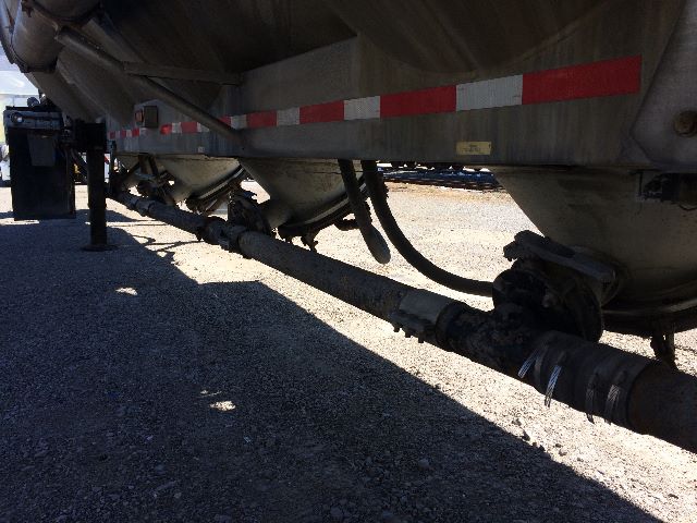 Pneumatic dry bulk trailer undercarriage with visible suspension and hose lines, side view showing tanker and lower piping.