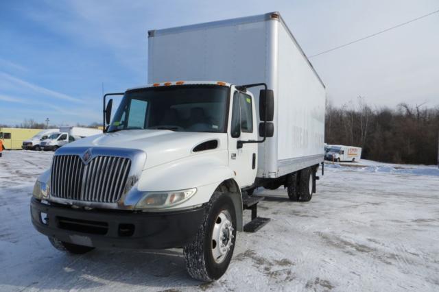 2003 International 4300 box truck in a snowy lot, white cab, large rectangular box body, black front bumper and grille.