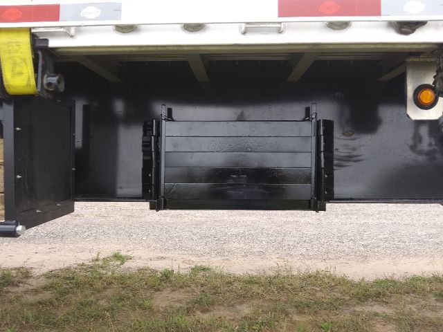 Trailer undercarriage showing a black rectangular plastic storage bin or toolbox in the center bottom, with side brackets and a flatbed surface above.