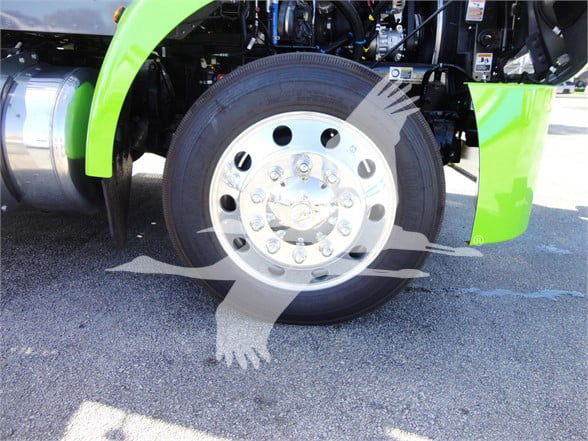 Peterbilt 337 truck wheel and front fender with lime green body panel visible, heavy duty chrome wheel and tire, engine bay area and suspension components visible.
