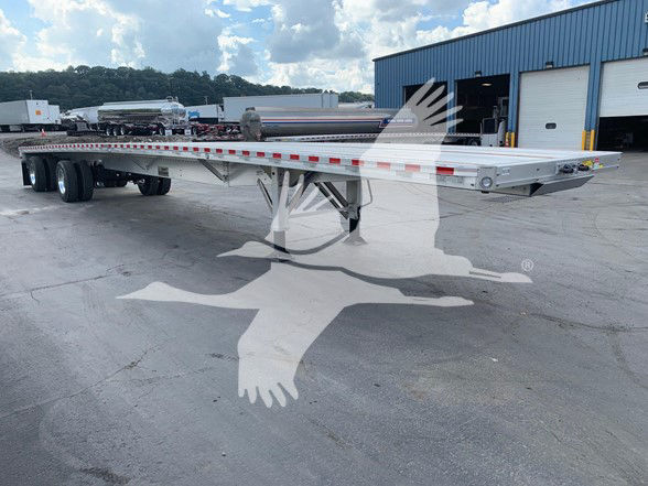 Flatbed trailer with sliding rear axle, aluminum deck, and landing gear visible at a truck yard. VIN 1RNF53A23TR074328 and stock TR074328 visible in listing header.