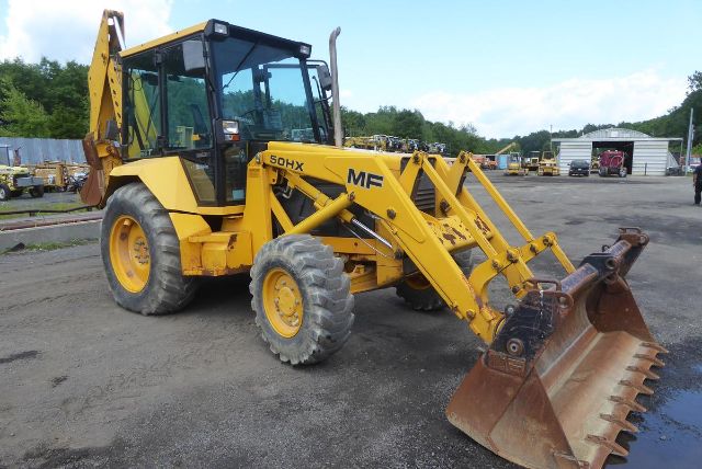 Massey Ferguson 50HX loader backhoe in yellow with front bucket and enclosed cab, parked on dirt lot; 'SOHX' and 'MF' decals visible on loader arm.