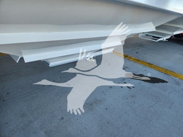 Front underside of a white hopper trailer with a shadow of a flying goose logo. Visible text includes VIN label, stock number, category, type, and condition details.