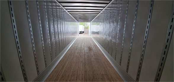 Trailer interior showing wooden floor and metal sidewalls with guiding tracks, van trailer empty perspective view
