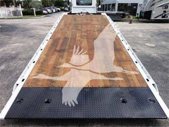 Flatbed truck deck with wooden planks and black diamond plate at the front, rear perspective from top of bed.