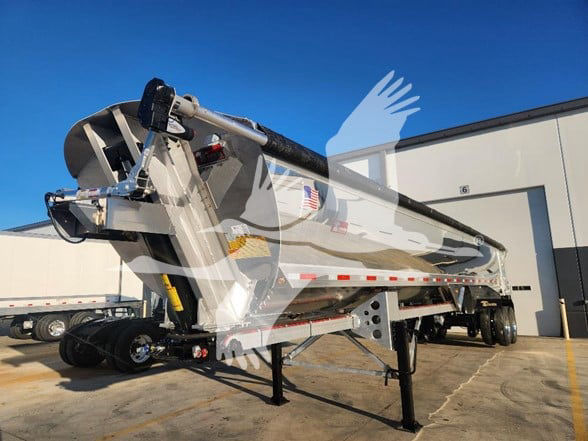 Dump trailer in-service showing side view with storage tank and hitch, aluminum body and support legs.